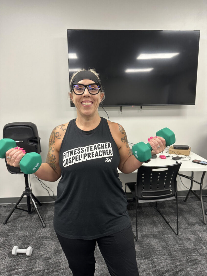 A woman is holding green dumbbells in her hands.